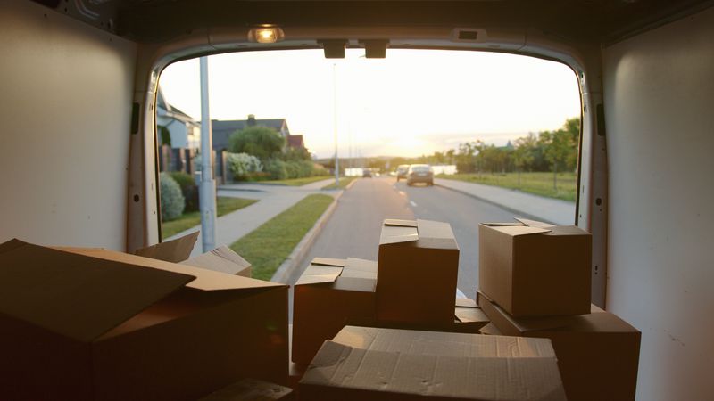 Cajas de cartón cargadas en una furgoneta con las puertas traseras abiertas al atardecer
