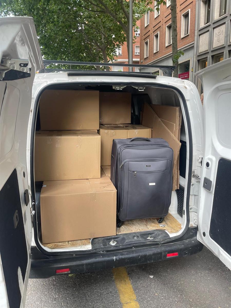 Furgoneta de LetsBoxIt cargada con cajas y una maleta grande, aparcada en la calle frente a una residencia universitaria de Madrid