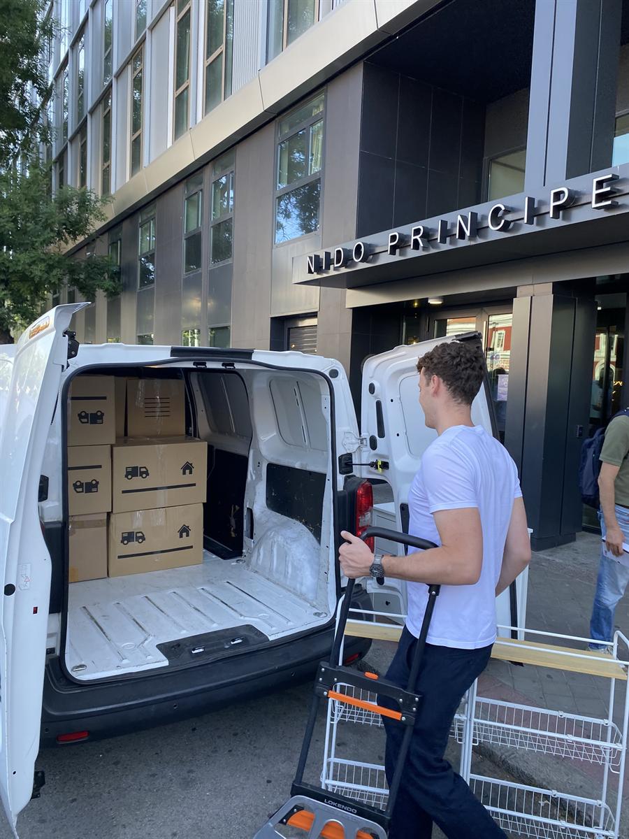 Jose, cofundador de LetsBoxIt, con una carretilla junto a la furgoneta cargada de cajas de la marca, entregando en la residencia Nido Príncipe Pío de Madrid
